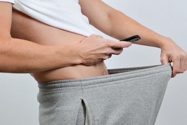 Un hombre mira un pene agrandado a través de sus pantalones.